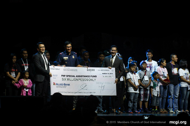 Kuya Daniel Razon (L) with Mr. Atom Henares (R) turns over the 6M check to PNP Representative Nestor Quinsay during the Songs For Heroes Benefit Concert supported by MCGI on March 19, 2015.  (Photo courtesy of Photoville International)