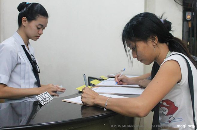 A female guest logging her name at the attendance table in the Muñoz Coordinating Center. (Photo courtesy of Photoville International)