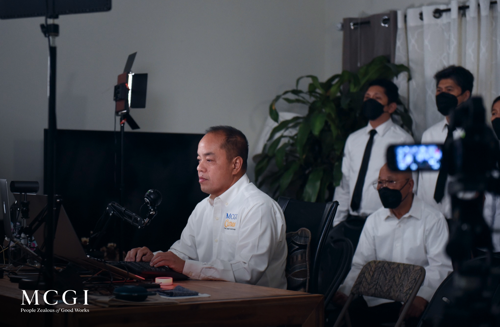 The image shows Brother Josel Mallari, an MCGI Helper of the Ministry, behind His laptop while attending an MCGI gathering.